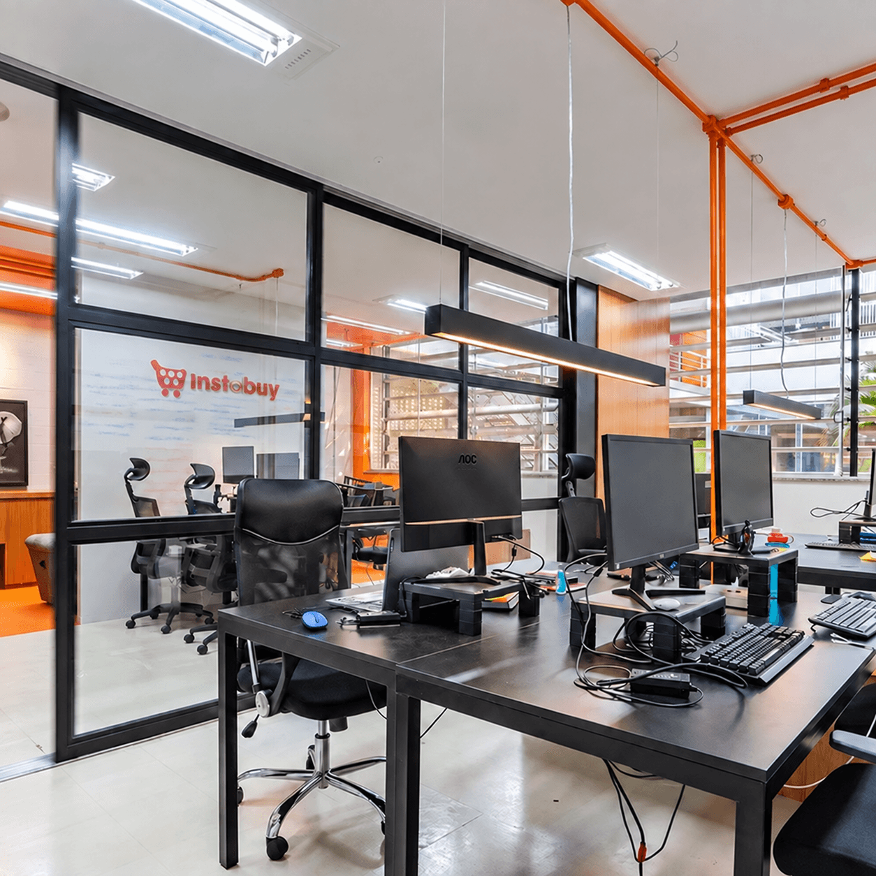 Escritório da Instabuy, com mesas de trabalho e o logo da empresa na parede de vidro